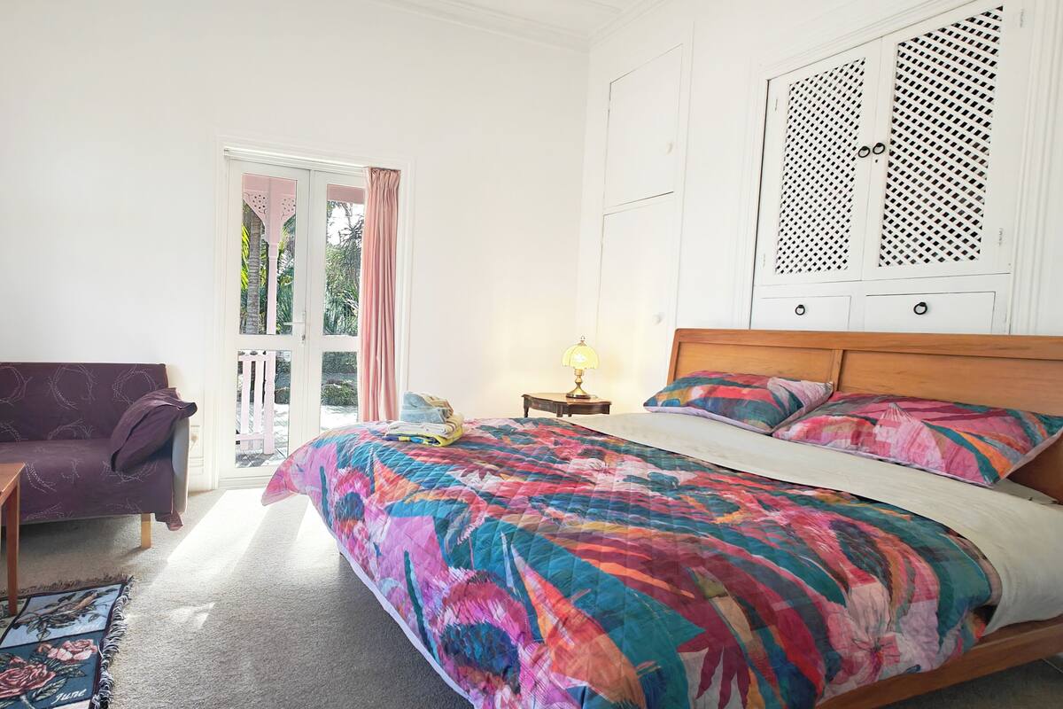 Ein Schlafzimmer mit einem Bett, einer Couch, einem kleinen Tisch und einem Fenster mit Vorhängen.