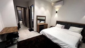 A modern hotel room with a large bed, a desk, a mirror, and a wardrobe. - Experience luxury & comfort at Maison D'Ophir's 3 bedrooms, billiard and more (Dakar)
