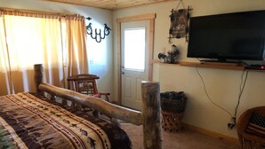 A room with a bed, a television, a door, and a window with curtains. - {Aspen Chalet} Hot Tub, Tesla Charger, Near Deadwood! (Lead)