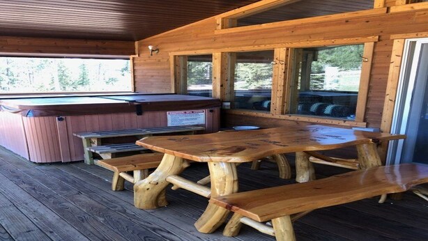 A wooden deck with a hot tub and picnic tables. - {Aspen Chalet} Hot Tub, Tesla Charger, Near Deadwood! (Lead)