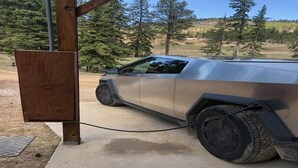 A vehicle parked next to a wooden structure, possibly a charging station, with a clear view of a forested area in the background. - {Aspen Chalet} Hot Tub, Tesla Charger, Near Deadwood! (Lead)