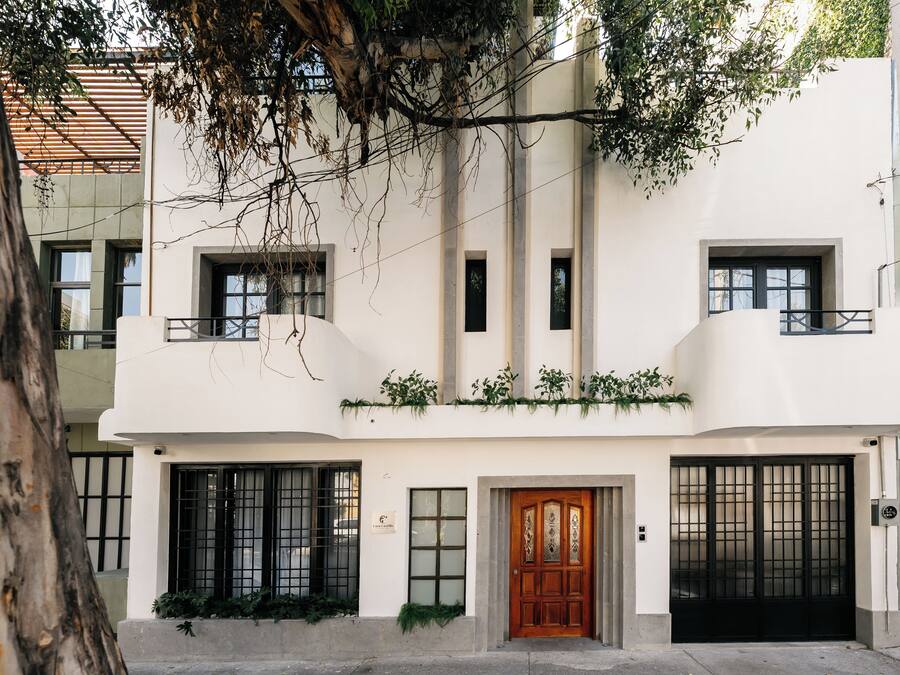 A modern two-story building with a white facade, large windows, and a wooden door.