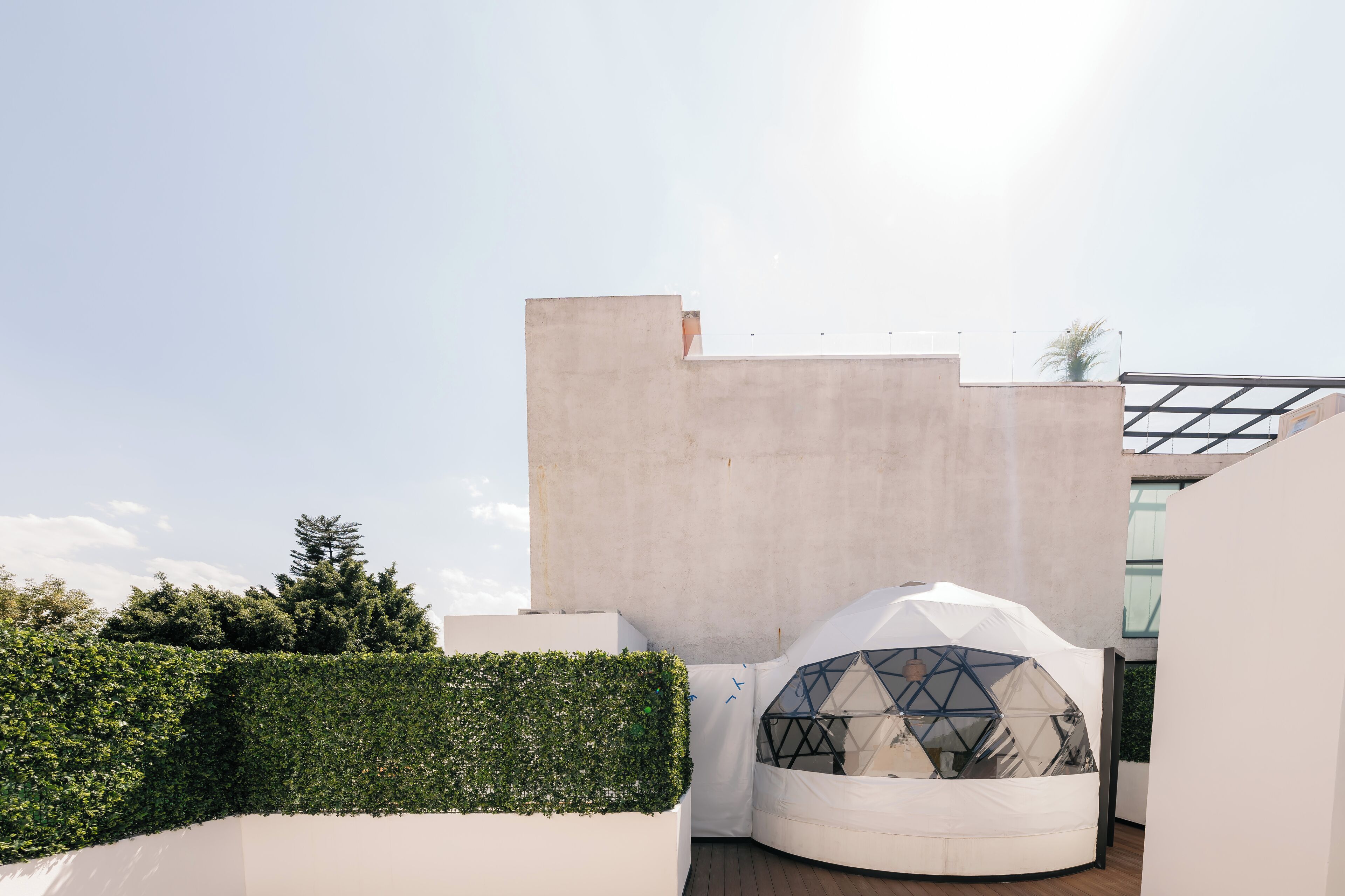 Une structure architecturale moderne dotée d’un dôme géométrique et d’un mur blanc.