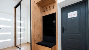 Een kamer met een houten bank, een donkere deur en een glazen schuifdeur.
