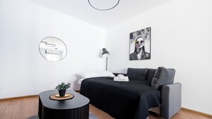 Een moderne slaapkamer met een bed, een nachtkastje, een ronde spiegel, een vloerlamp en een schilderij aan de muur.