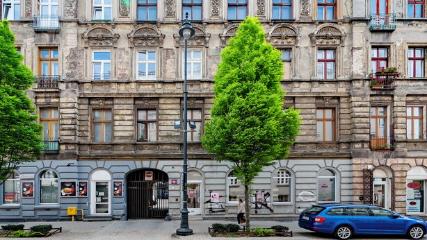 Ein historisches Gebäude mit aufwendigen architektonischen Details, einem ehrwürdigen Eingangstor und einem abgestellten Auto.