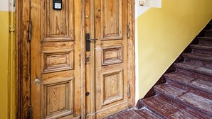 Eine hölzerne Doppeltür mit Messinggriffen und Schloss, eine gelbe Wand und eine Holztreppe.