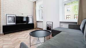 Ein modernes Wohnzimmer mit einer schwarzen Unterhaltungsecke, einem grauen Sofa und einem runden, schwarzen Couchtisch.