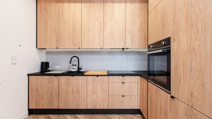 Eine moderne Küche mit Holzausstattung, einer schwarzen Arbeitsplatte, einer Spüle und einem Backofen.