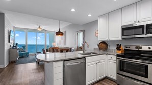A modern kitchen with white cabinets, stainless steel appliances, and a large island. - 2 Bedroom Lighthouse w/Bunk,  3 Pools! Direct Beachfront.  Free Daily Activities (Gulf Shores)