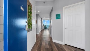 A hallway with a blue door, white walls, and a wooden floor. - 2 Bedroom Lighthouse w/Bunk,  3 Pools! Direct Beachfront.  Free Daily Activities (Gulf Shores)
