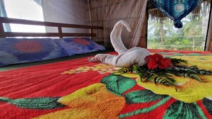 Un lit recouvert d’une courtepointe à motifs floraux colorés, décoré d’un cygne blanc et agrémenté d’un bouquet de fleurs.