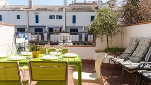 An outdoor patio with a table set for dining, chairs, and a view of buildings in the background. - WELCS CASA ADOSADA 241 EMP con terraza al canal (Empuriabrava)