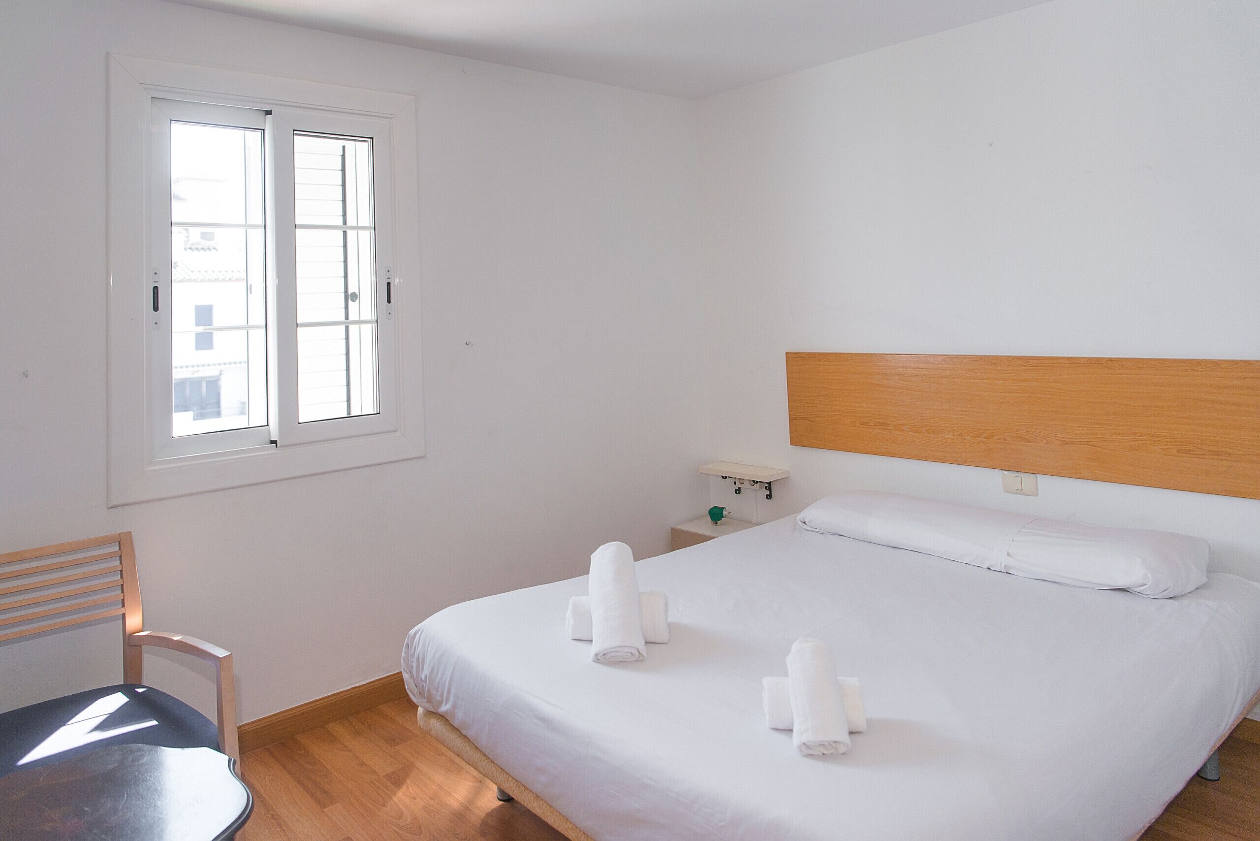 Ein Hotelzimmer mit einem Bett, einem Sessel, einem Nachttisch und einem Fenster.