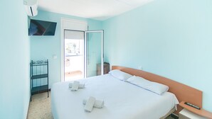 A neatly made bed with white linens and pillows, a bedside table with a remote control, and a small wooden nightstand. - WELCS CASA 242 EMP con piscina y vista al canal (Empuriabrava)