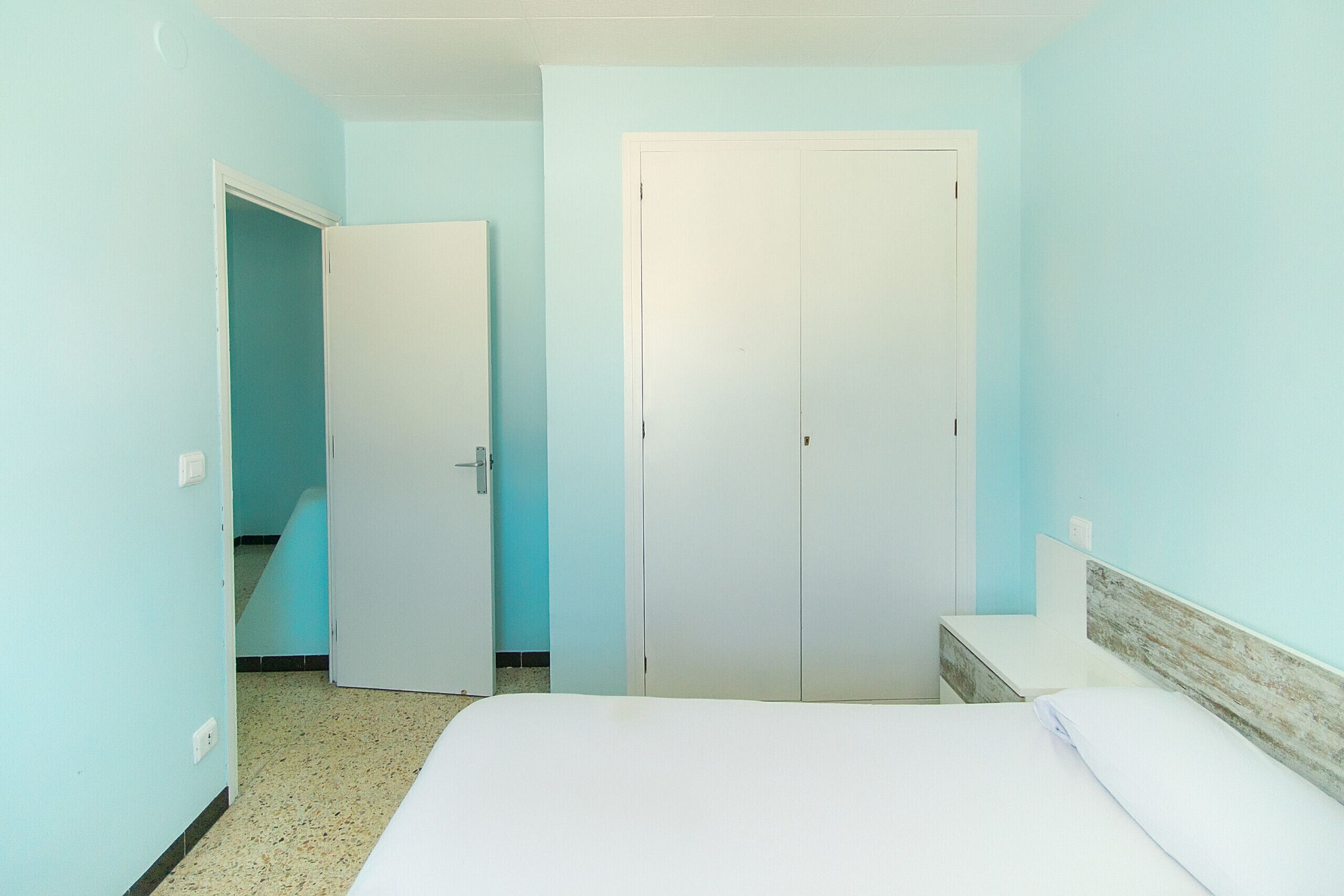 A bedroom with a bed, a wardrobe, and a bathroom door.