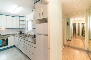 Kitchen features a refrigerator, oven, and sink, with a convenient connection to the hallway.