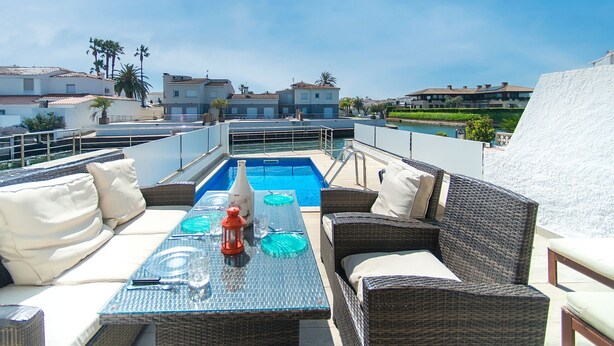 A rooftop terrace with a pool, wicker furniture, and a view of surrounding buildings. - WELCS CASA 242 EMP con piscina y vista al canal (Empuriabrava)
