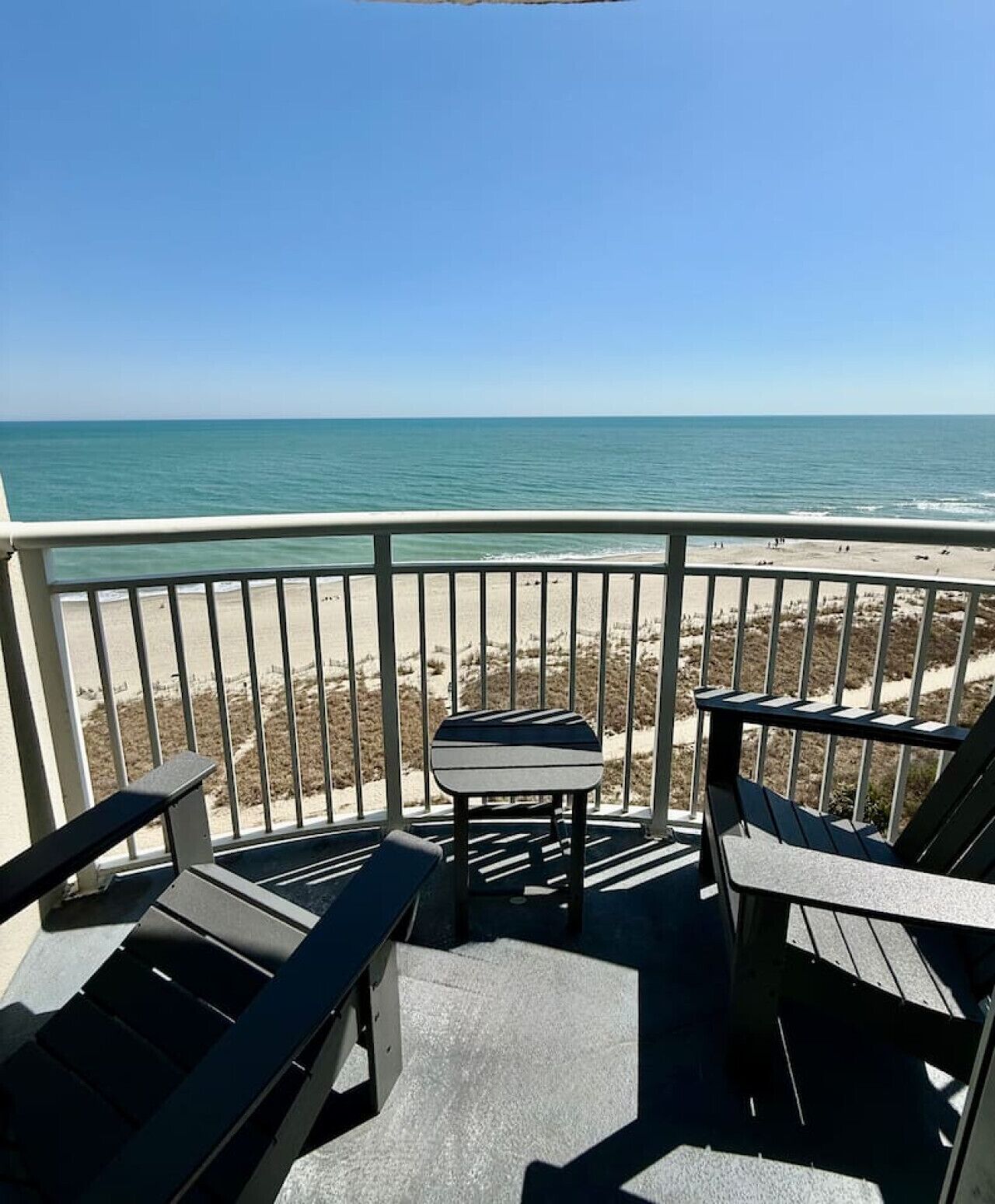 A balcony with a view of the beach and ocean.
