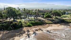 A coastal area with a sandy beach, a playground, and a view of distant mountains.