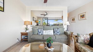 A living room with a grey sofa, a coffee table with a plant, and a ceiling fan.