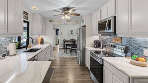 Une cuisine moderne avec des meubles blancs, un réfrigérateur en acier inoxydable, un four à micro-ondes et une cuisinière.