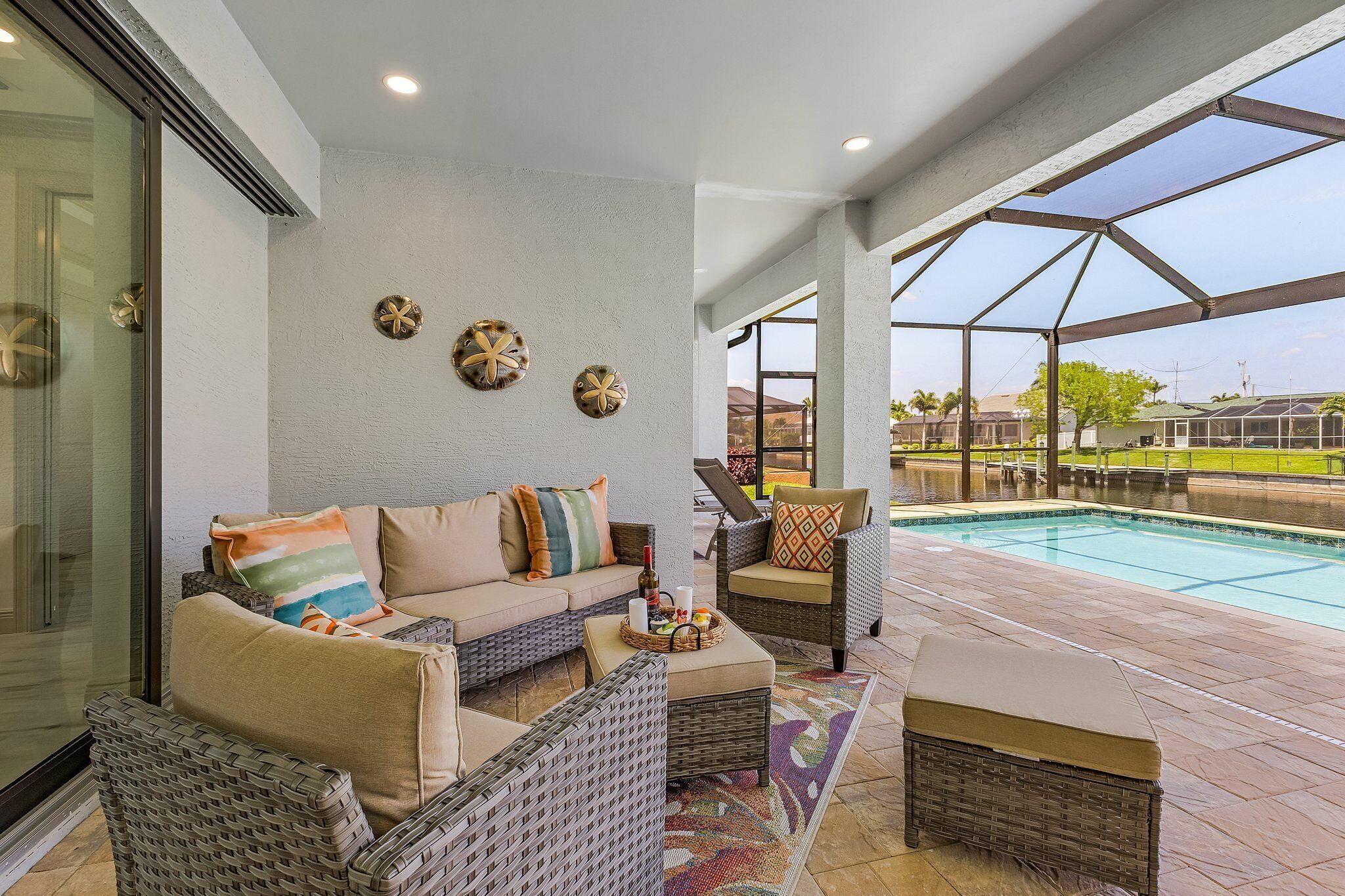 A covered outdoor area with a pool, wicker furniture, and a glass door leading to a poolside area.