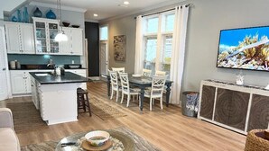 Une cuisine moderne avec des meubles blancs, un îlot central et un coin repas avec des chaises blanches.