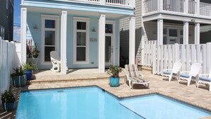 Un espace piscine comprenant une piscine, des chaises longues et un patio couvert.