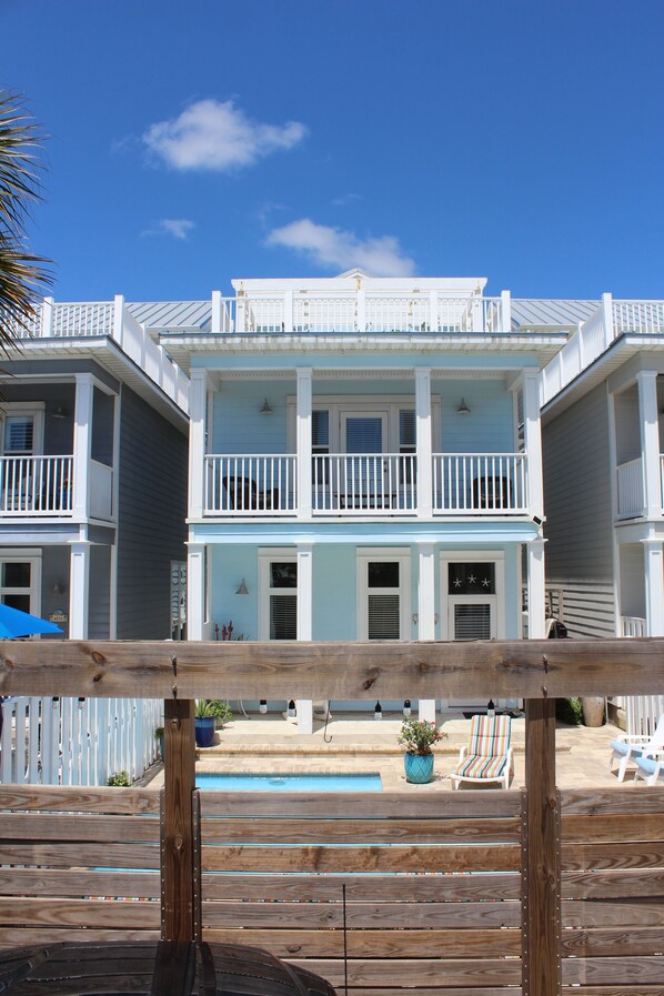 A two-story building with balconies, a pool, and outdoor seating.