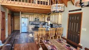 A spacious kitchen with wooden cabinets, a central island, and a dining area with a wooden table and benches. - Pocono Private lake setting with, Hot Tub, boat dock, fishing, Swimming, Canoe (Cresco)