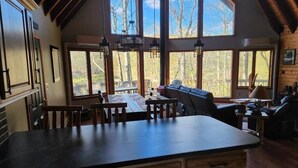 A spacious kitchen with a large island, wooden cabinets, and a view of the outdoors through large windows. - Pocono Private lake setting with, Hot Tub, boat dock, fishing, Swimming, Canoe (Cresco)