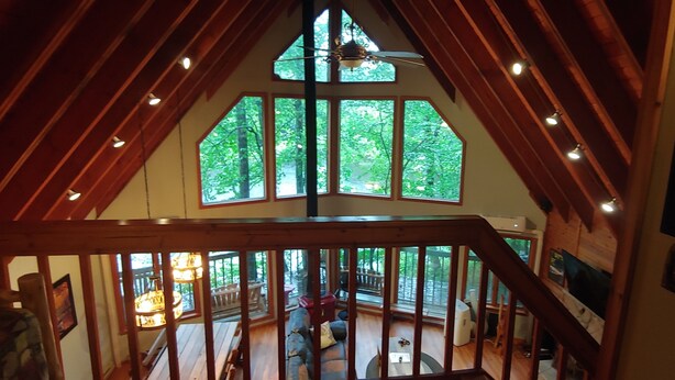 A high-ceilinged room with large windows, wooden beams, and a view of the outdoors. - Pocono Private lake setting with, Hot Tub, boat dock, fishing, Swimming, Canoe (Cresco)