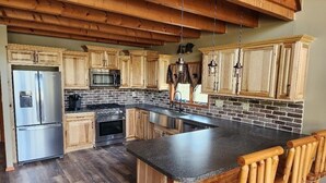 A kitchen with wooden cabinets, a granite countertop, a stainless steel refrigerator, a microwave, and a stove. - Pocono Private lake setting with, Hot Tub, boat dock, fishing, Swimming, Canoe (Cresco)