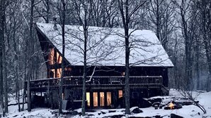 A cabin with a sloped roof, wooden exterior, and a deck. - Pocono Private lake setting with, Hot Tub, boat dock, fishing, Swimming, Canoe (Cresco)