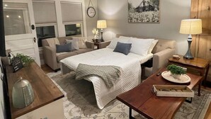 Une chambre confortable avec un grand lit, deux tables de chevet, une commode, une armoire en bois et un petit bureau avec une lampe.