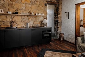 Una cocina con pared de piedra, armarios de madera y encimera negra.