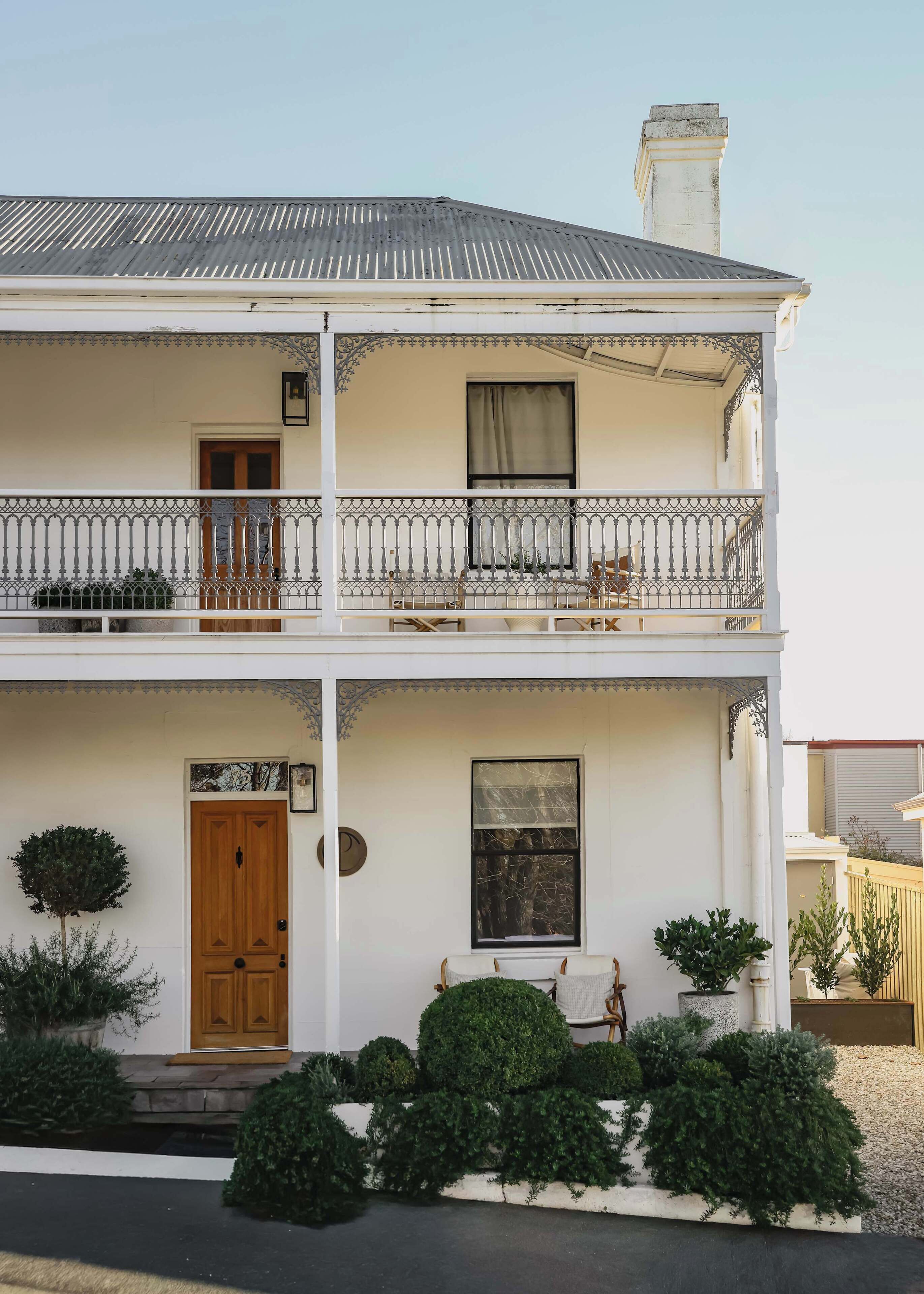 Un bâtiment à deux étages doté d’un balcon, d’une porte en bois et d’une fenêtre avec un rideau.