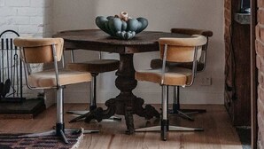 En matplats med ett runt bord, fyra stolar, en dekorativ skål i mitten och en hängande lampa.