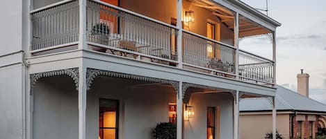 A two-story building with balconies, large windows, and a porch area.