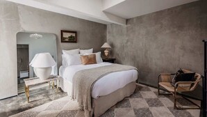 Ein modernes Schlafzimmer mit einem großen Bett, Nachttischlampen, einem Spiegel und einem Sessel.