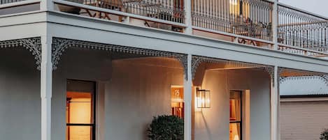 Un immeuble doté d’un balcon, de nombreuses fenêtres et d’une porte portant un numéro.