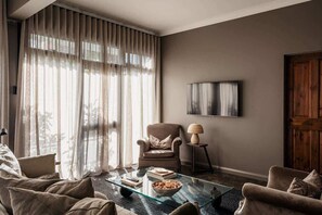 Relax in this inviting living space with a comfortable armchair, flat-screen TV, and cozy reading area.
