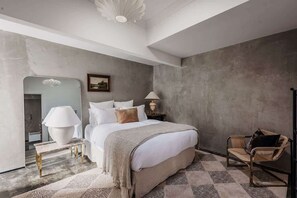Relax in a serene space with a large bed, bedside table, and comfortable chair.