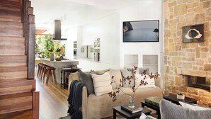 A living room with a stone fireplace, a sofa with cushions, a coffee table, and a TV mounted on the wall.