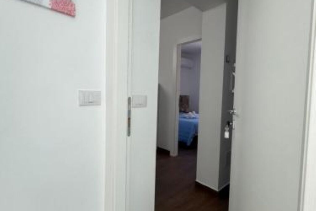 A hallway leading to a bedroom with a bed covered in a blue blanket.