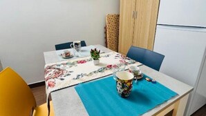 A small dining area with a table set for two, a chair, a cabinet, and a refrigerator. - DA REMO apartment :2 Bedroom Apartment with Balcony (Castellammare del Golfo)