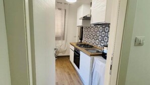 A narrow kitchen with a wooden floor, a stove, and a patterned backsplash. - DA REMO apartment :2 Bedroom Apartment with Balcony (Castellammare del Golfo)