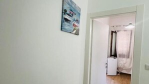 A room with a door leading to a bathroom. There is a painting on the wall depicting boats on water. - DA REMO apartment :2 Bedroom Apartment with Balcony (Castellammare del Golfo)