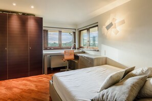 A bedroom with a bed, a desk, and a wardrobe.